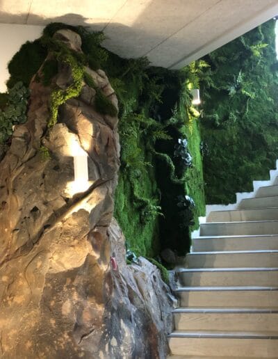 Création d’un mur végétal artificiel avec faux rocher dans un escalier pour une ambiance de forêt.